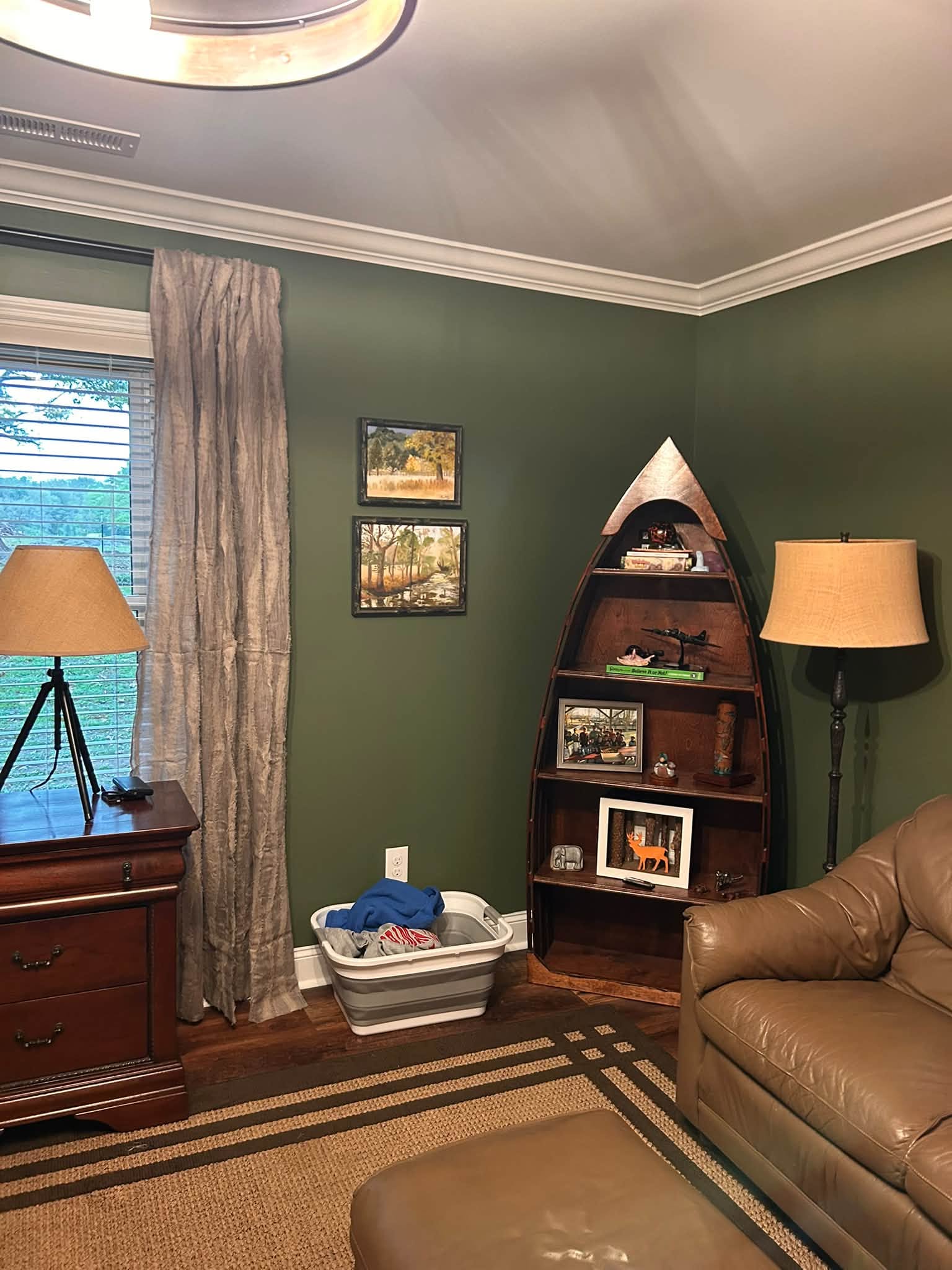 Cozy living room with deep green walls, wood furnishings and warm layered lighting
