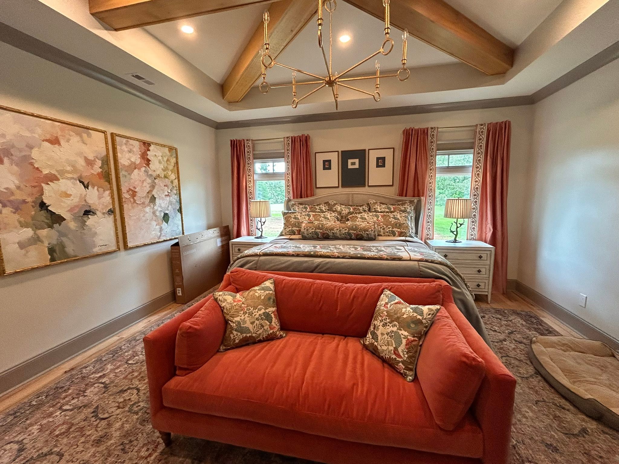 Warm bedroom interior with layered textiles, rust-colored seating and timber ceiling beams
